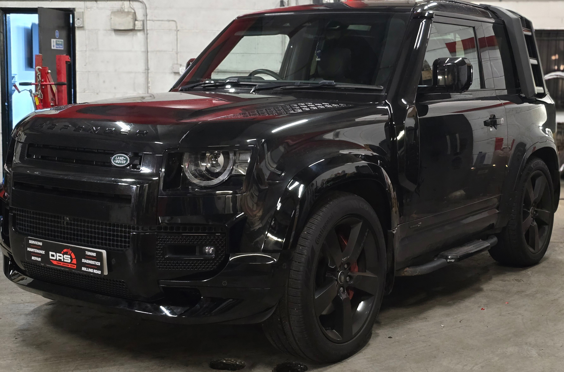 Black Land Rover Defender with DRS number plate in premium workshop